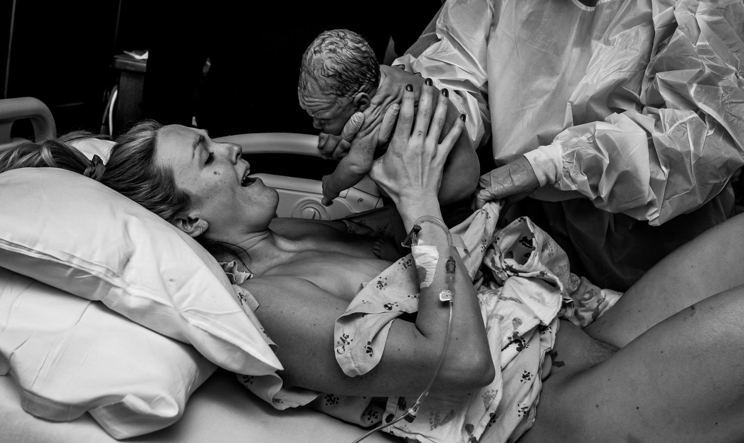 A touching moment between medical staff and a newborn baby in black and white.