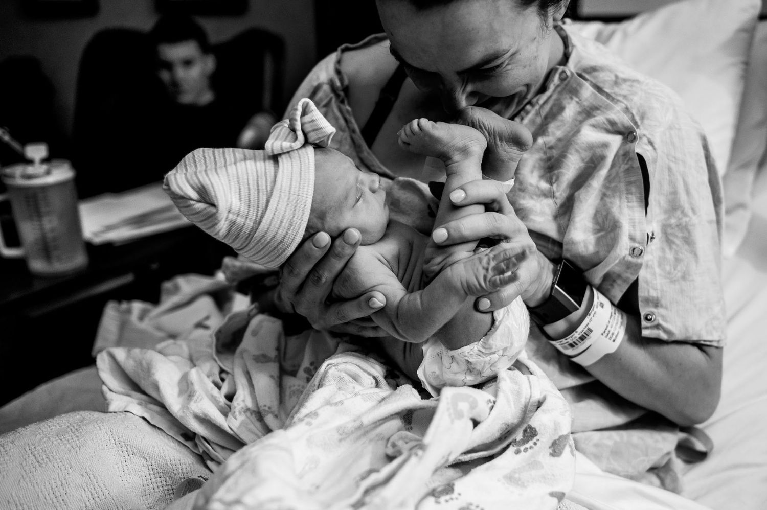 Black and white photo of a newborn baby being bottle fed in a medical setting.