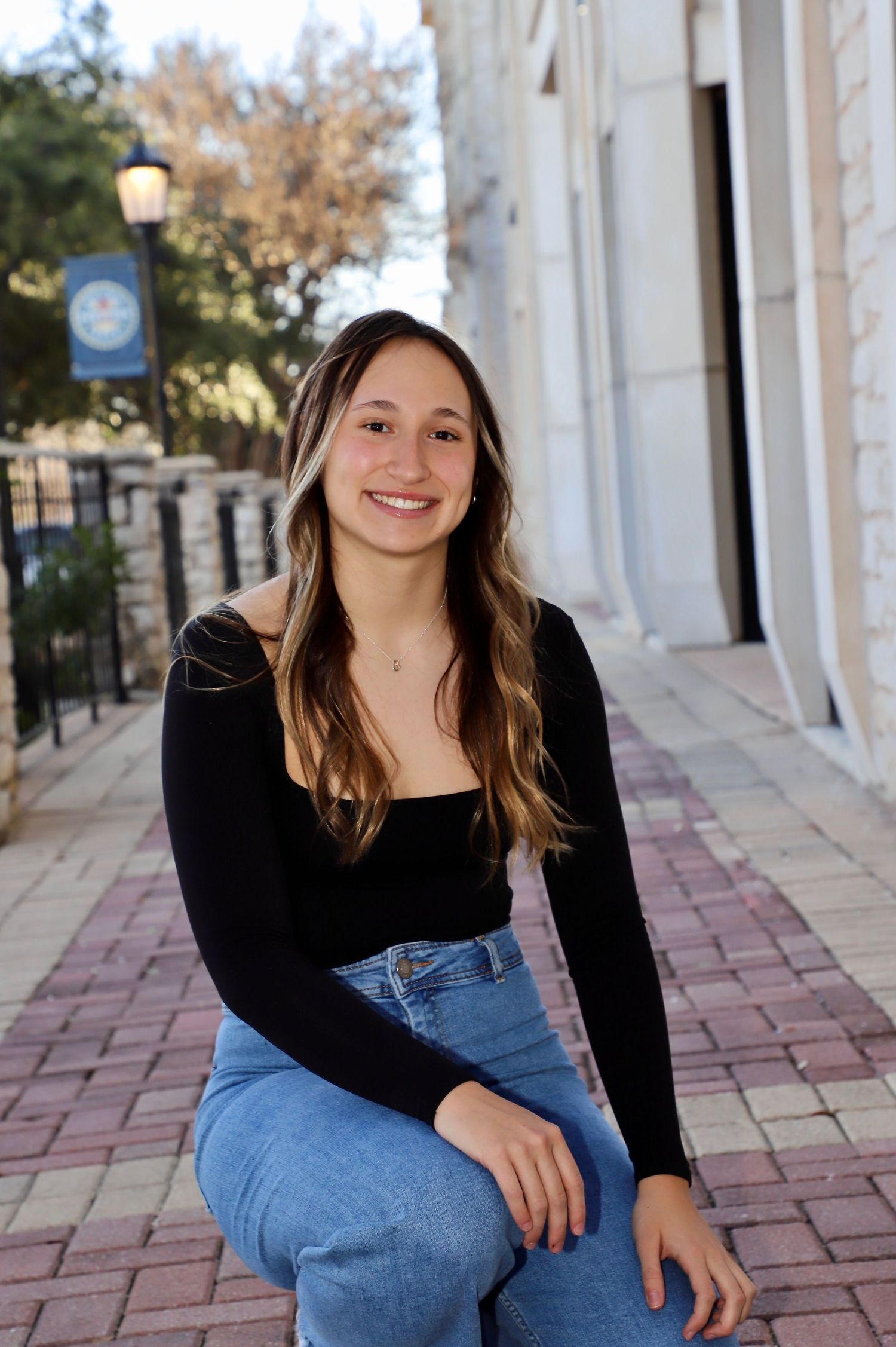 High school senior seated on a brick sidewalk in downtown Belton