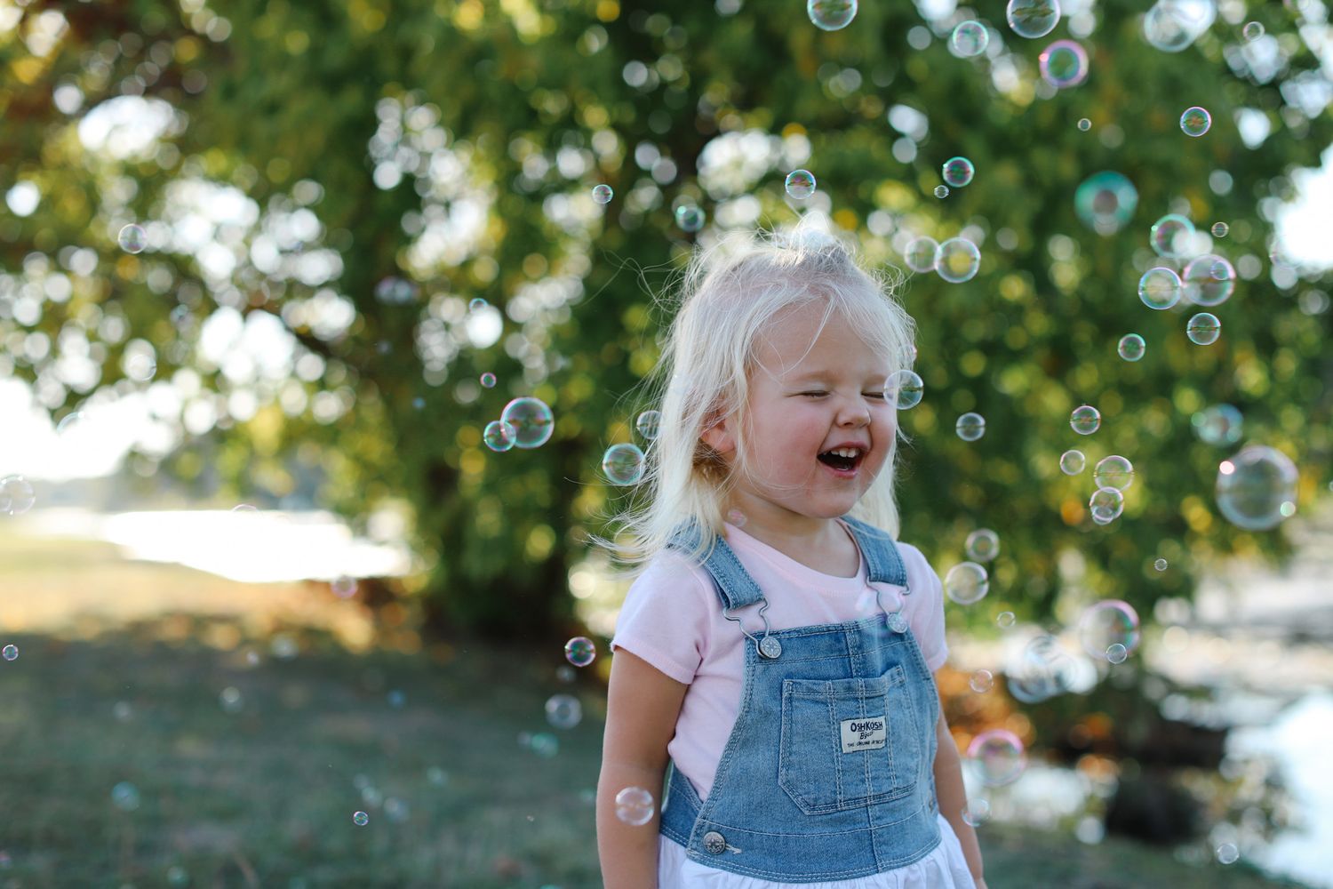 Laughing toddler surrounded by soap bubbles outdoors