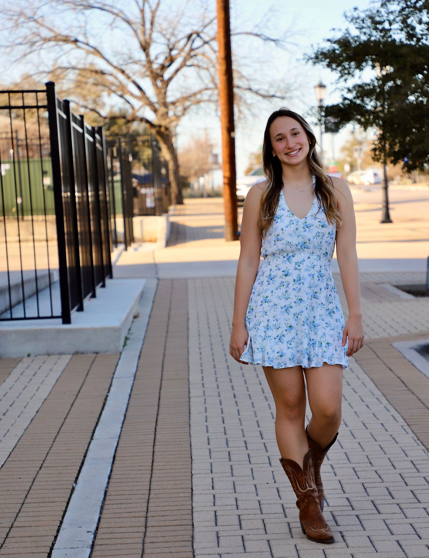 Smiling senior in a floral dress and cowboy boots walking downtown