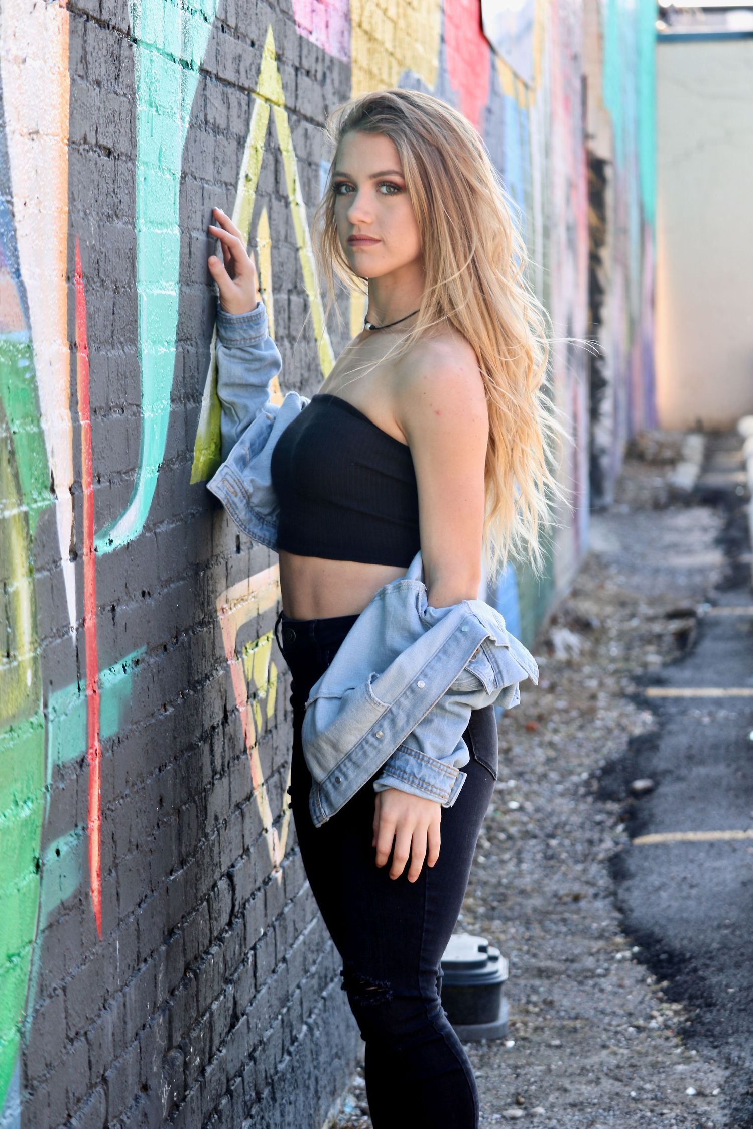 High school senior posing beside a colorful downtown mural