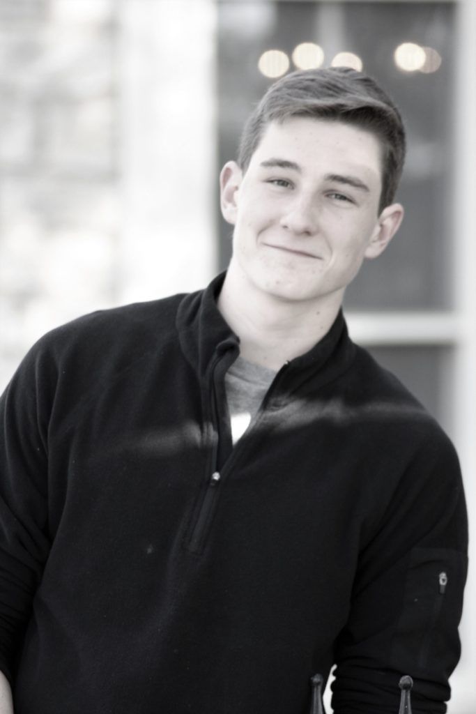 Black-and-white portrait of a smiling male high school senior