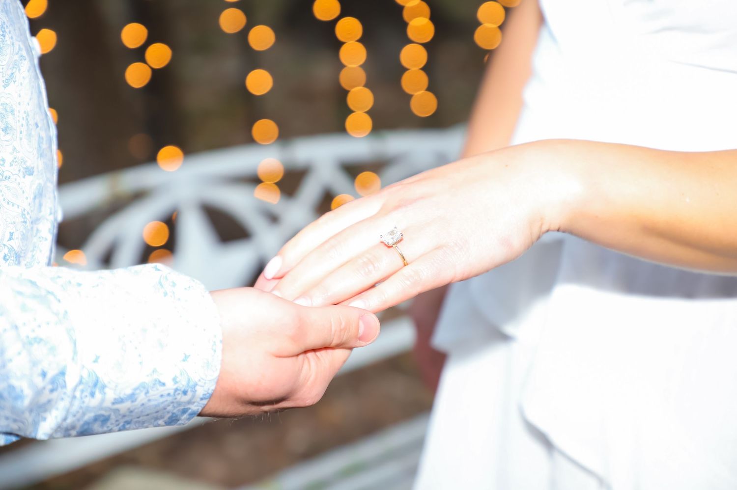 Close-up of an engagement ring as a couple holds hands