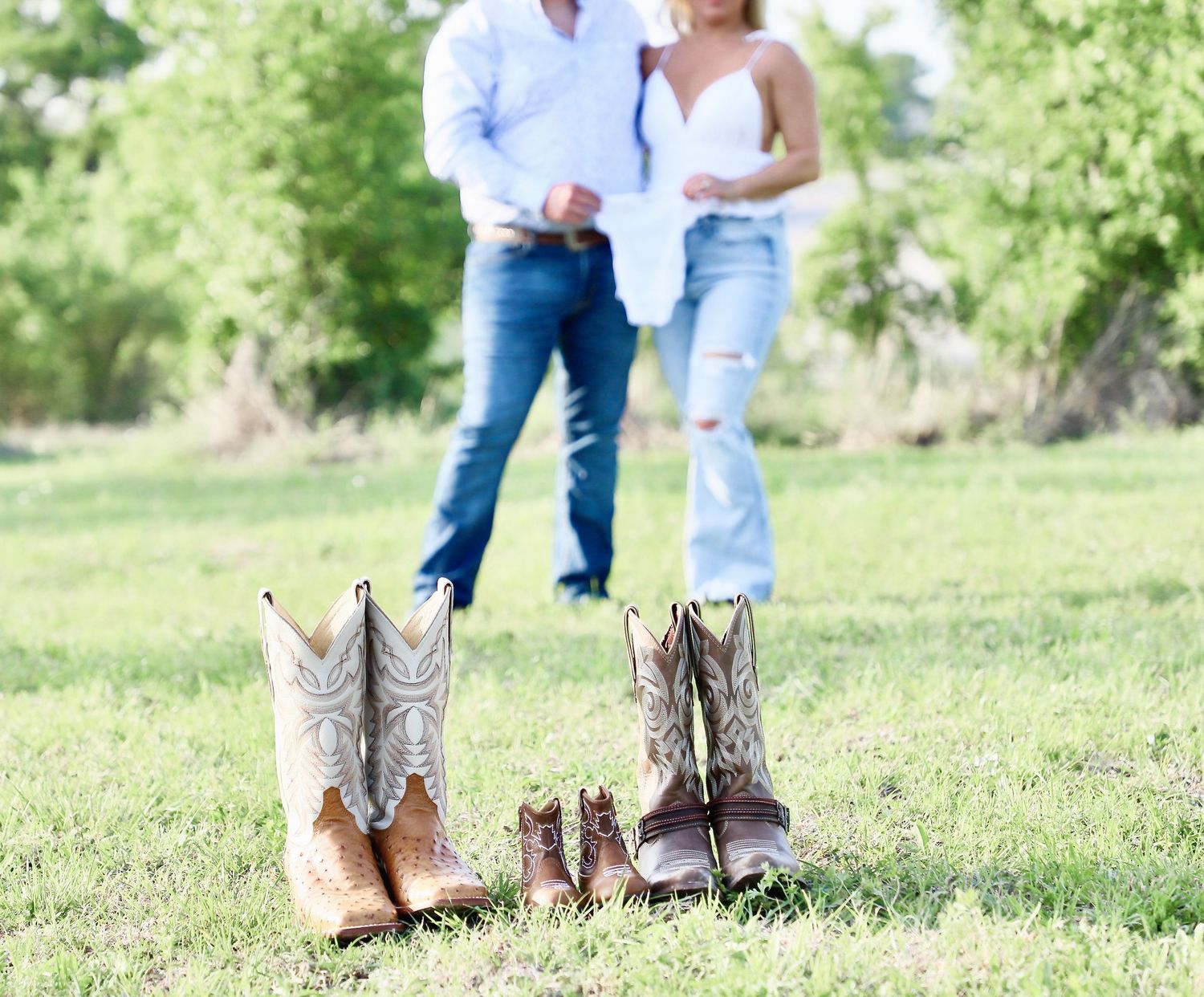 Adult and baby cowboy boots arranged in front of an expectant couple