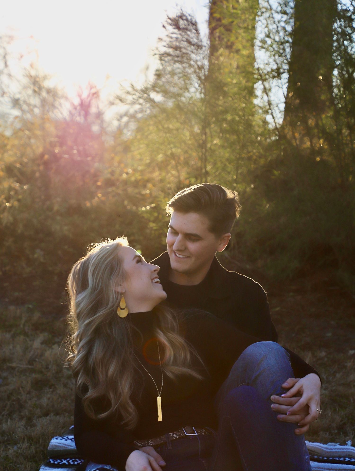 Couple sitting on a blanket and laughing together at golden hour