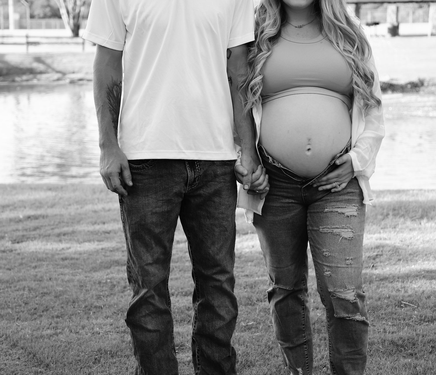 Black-and-white maternity portrait of an expectant couple holding hands