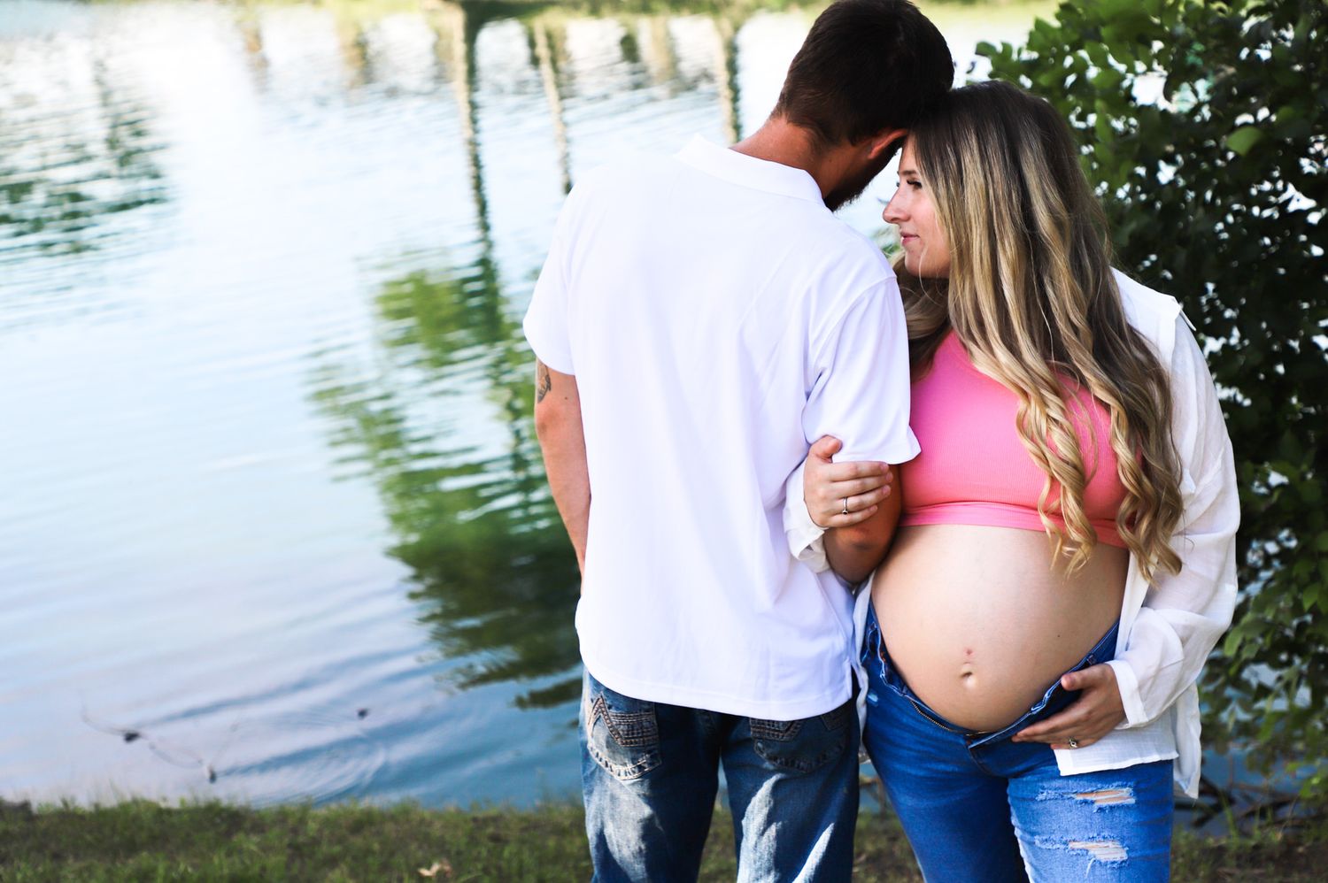 Expectant couple standing together beside a lake