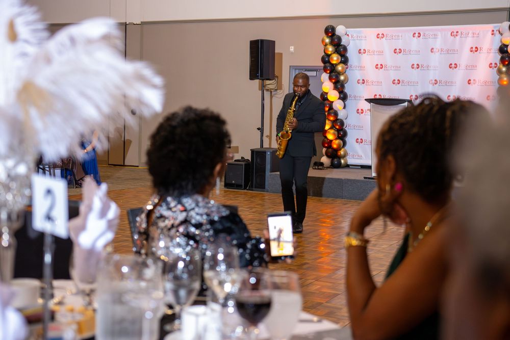 Musicians and guests celebrate at an indoor event with decorative balloons and lighting.