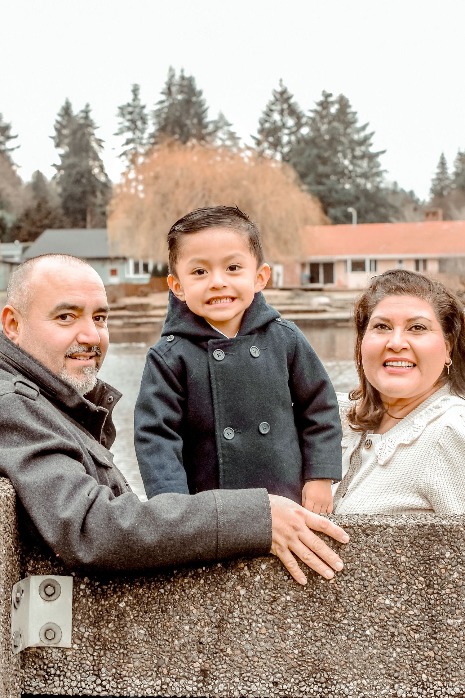 A playful sequence of photos showing a parent lifting and playing with a small child by a lake on a winter day.