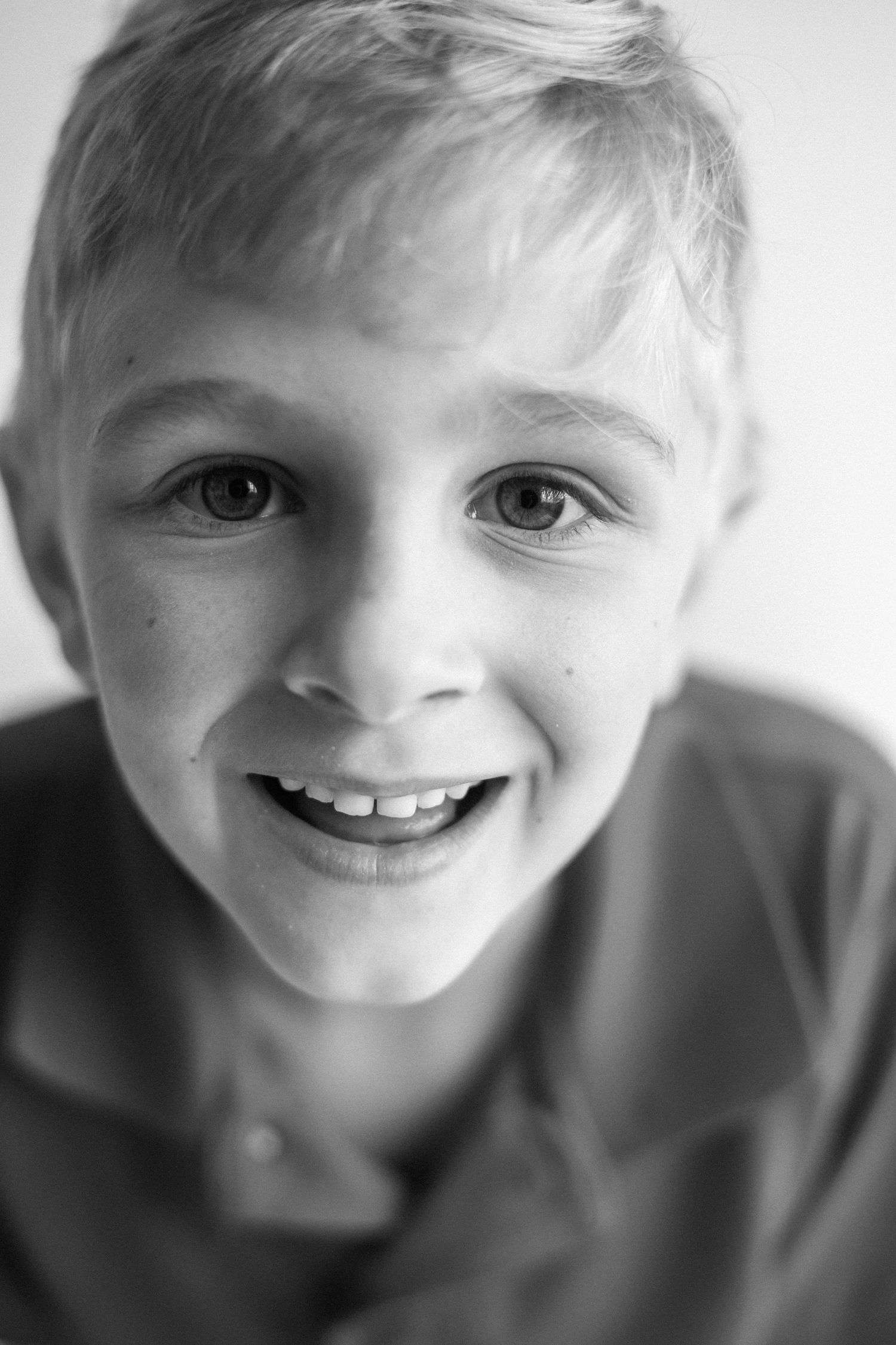 A black and white photo series shows a child with curly hair in a white shirt expressing joyful emotions.