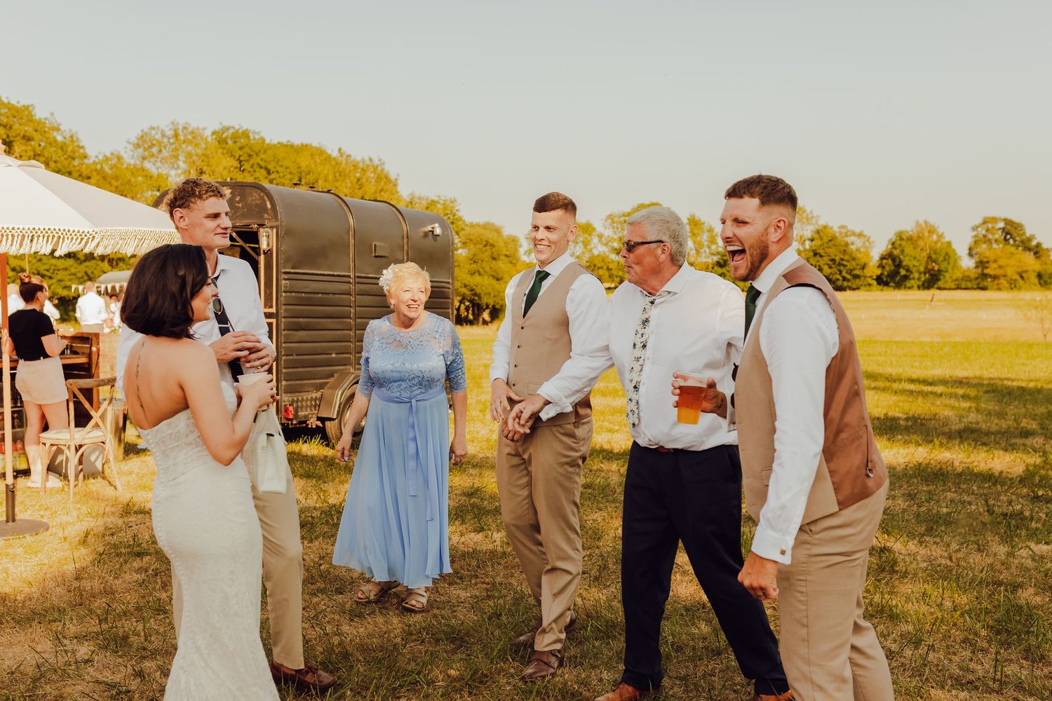 Candid moments of wedding guests laughing and connecting outdoors on the field.