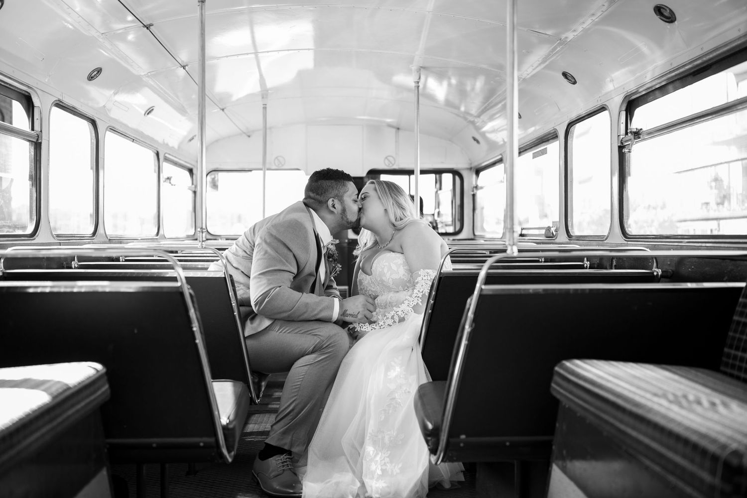A romantic couple shares a tender kiss while sitting together on a vintage bus.