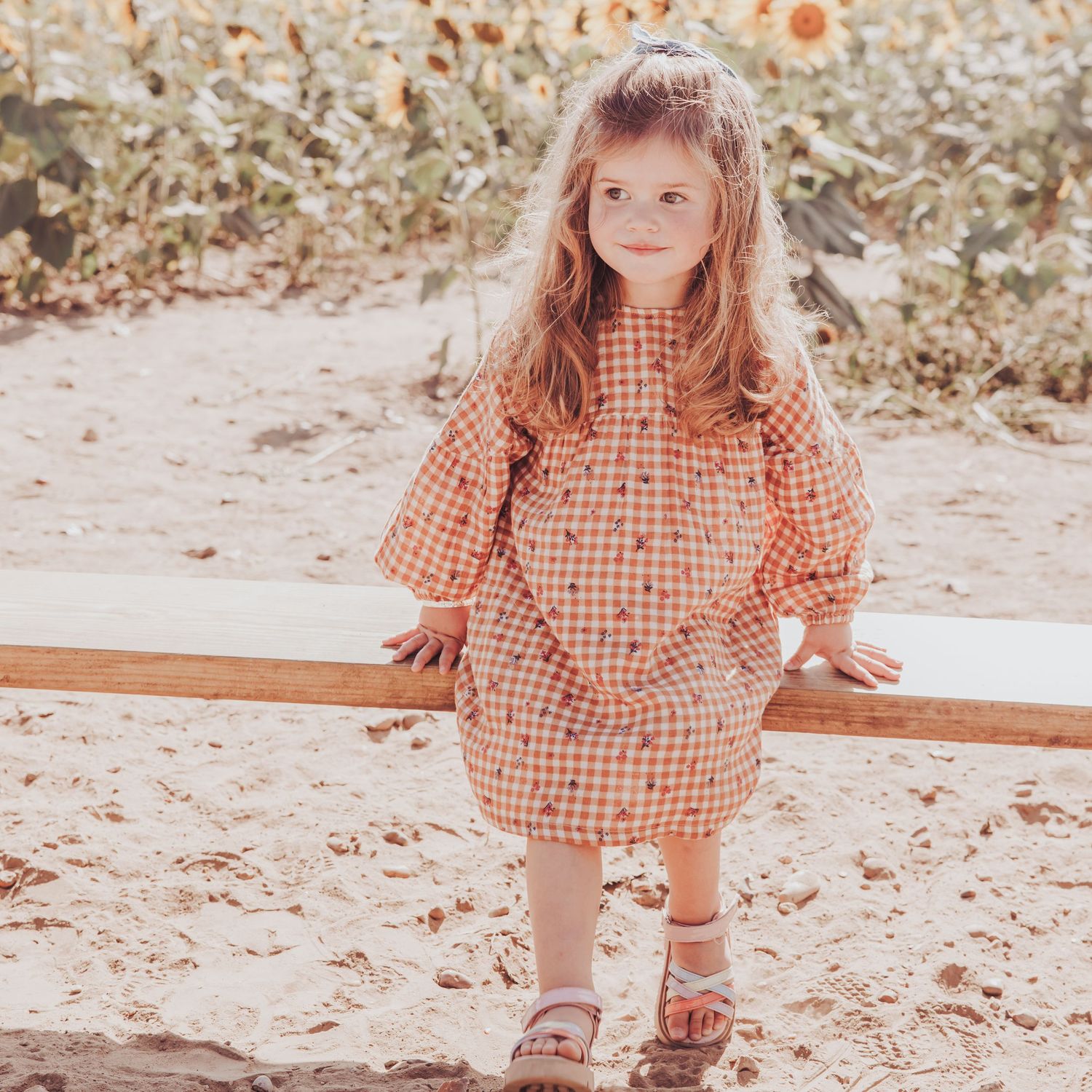 A natural outdoor child portrait capturing a young child in warm light surrounded by sunflowers