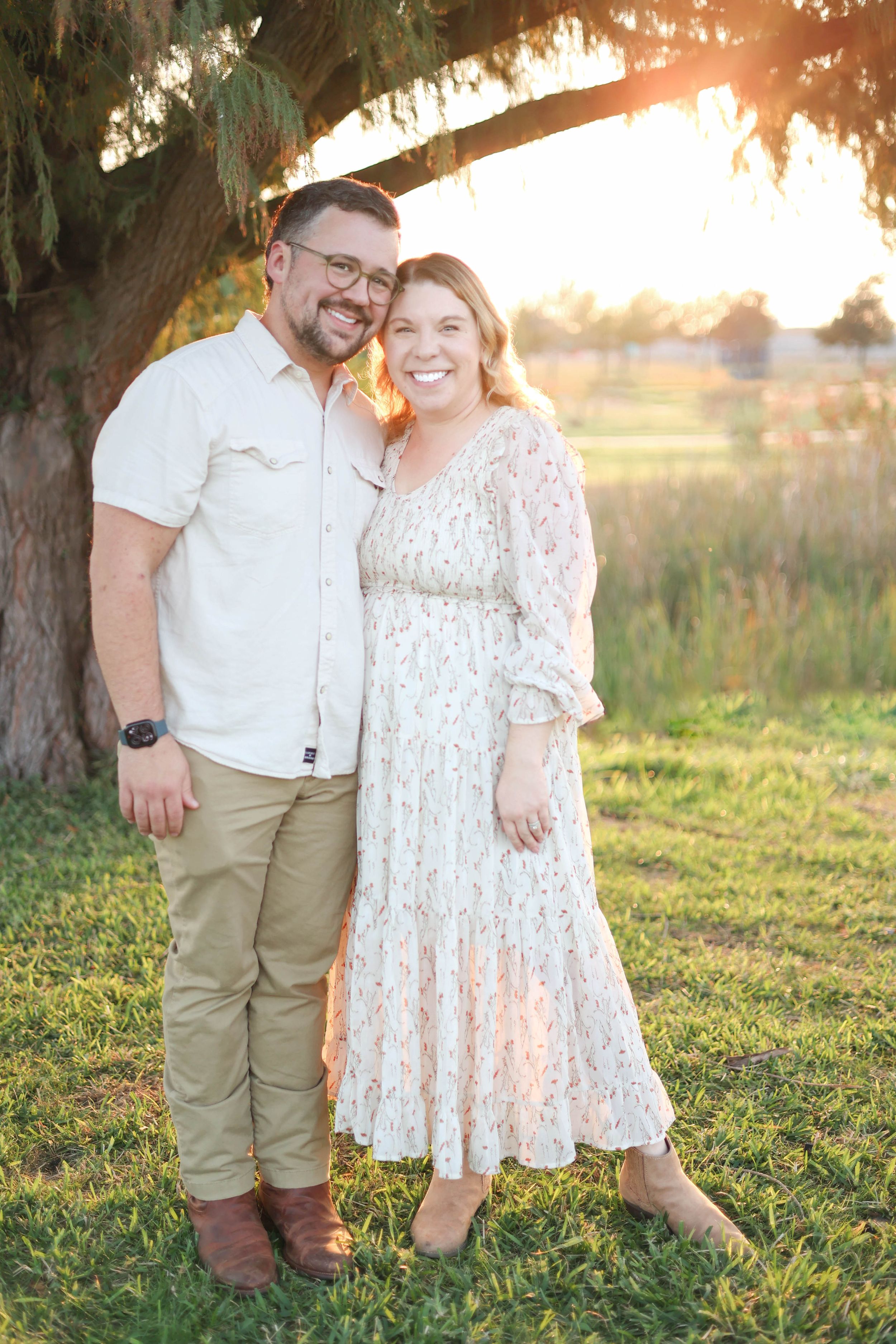 Couple under tree in park during golden hour.