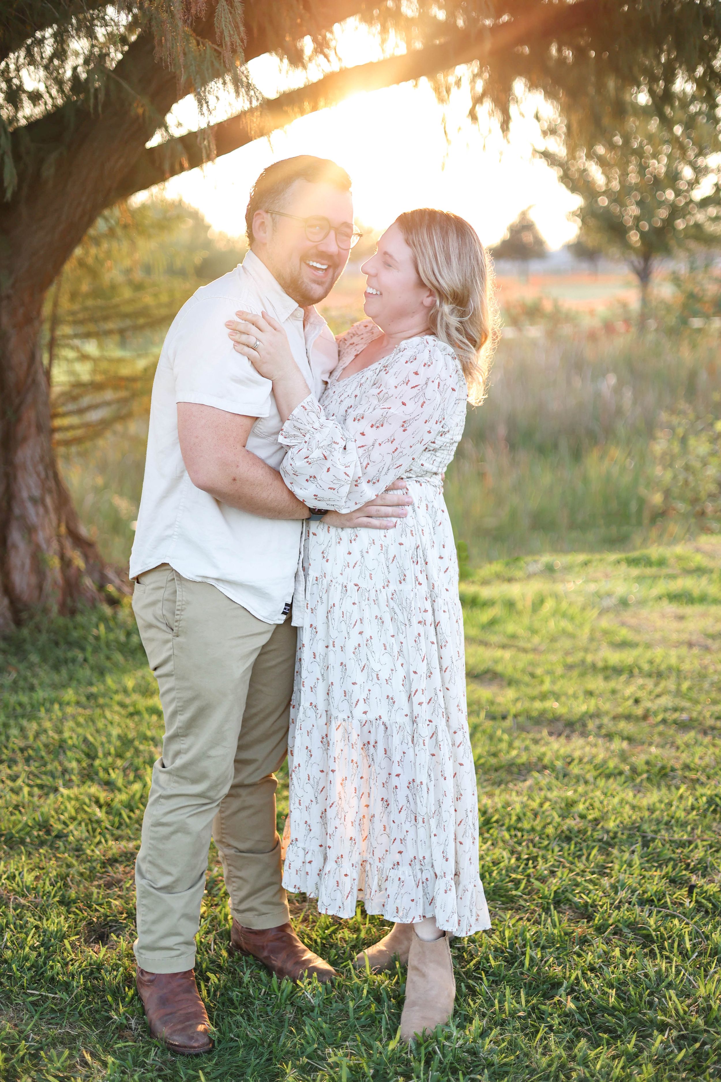 Couple under tree in park during golden hour.