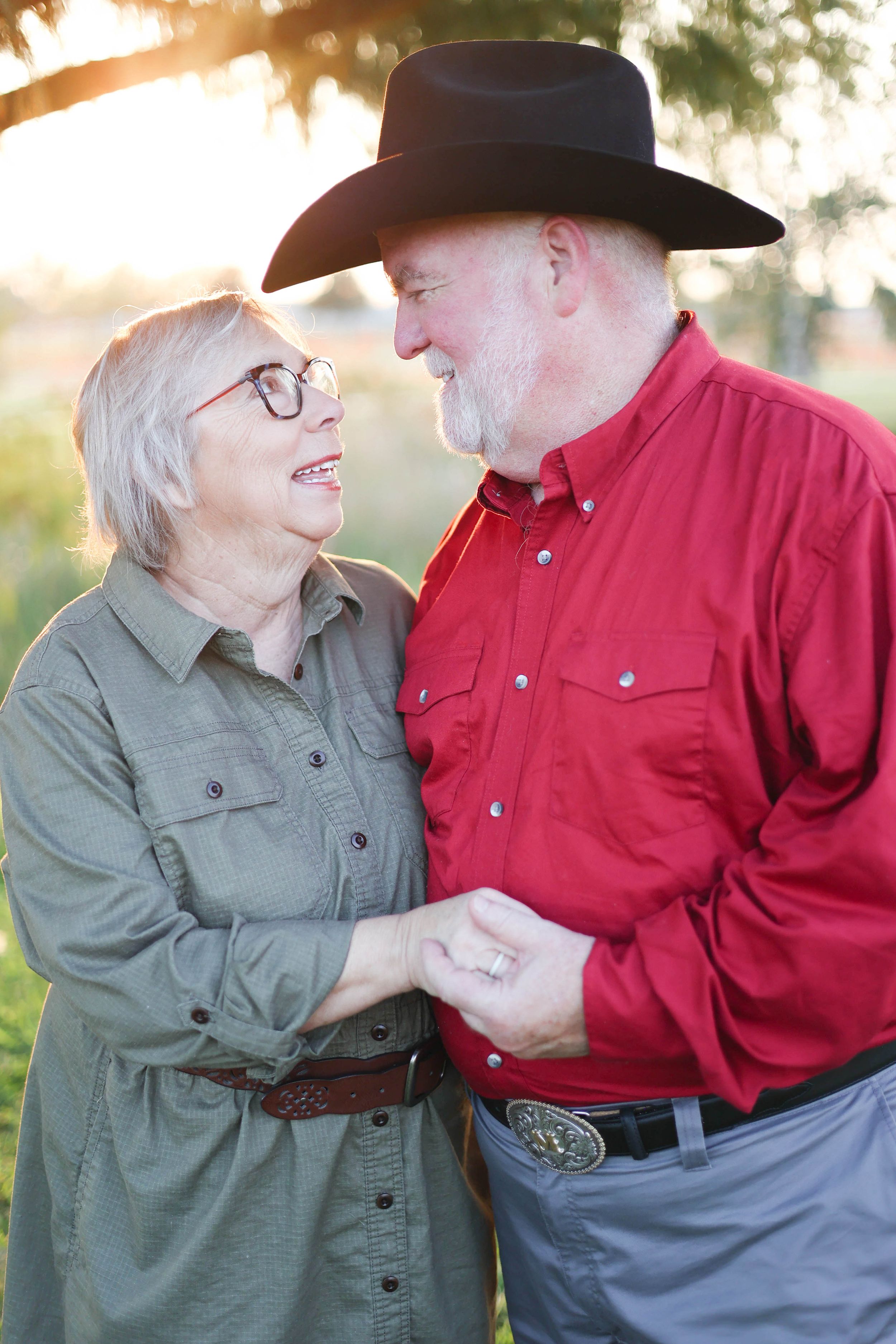 Couple gazing at each other under tree in golden hour glow.