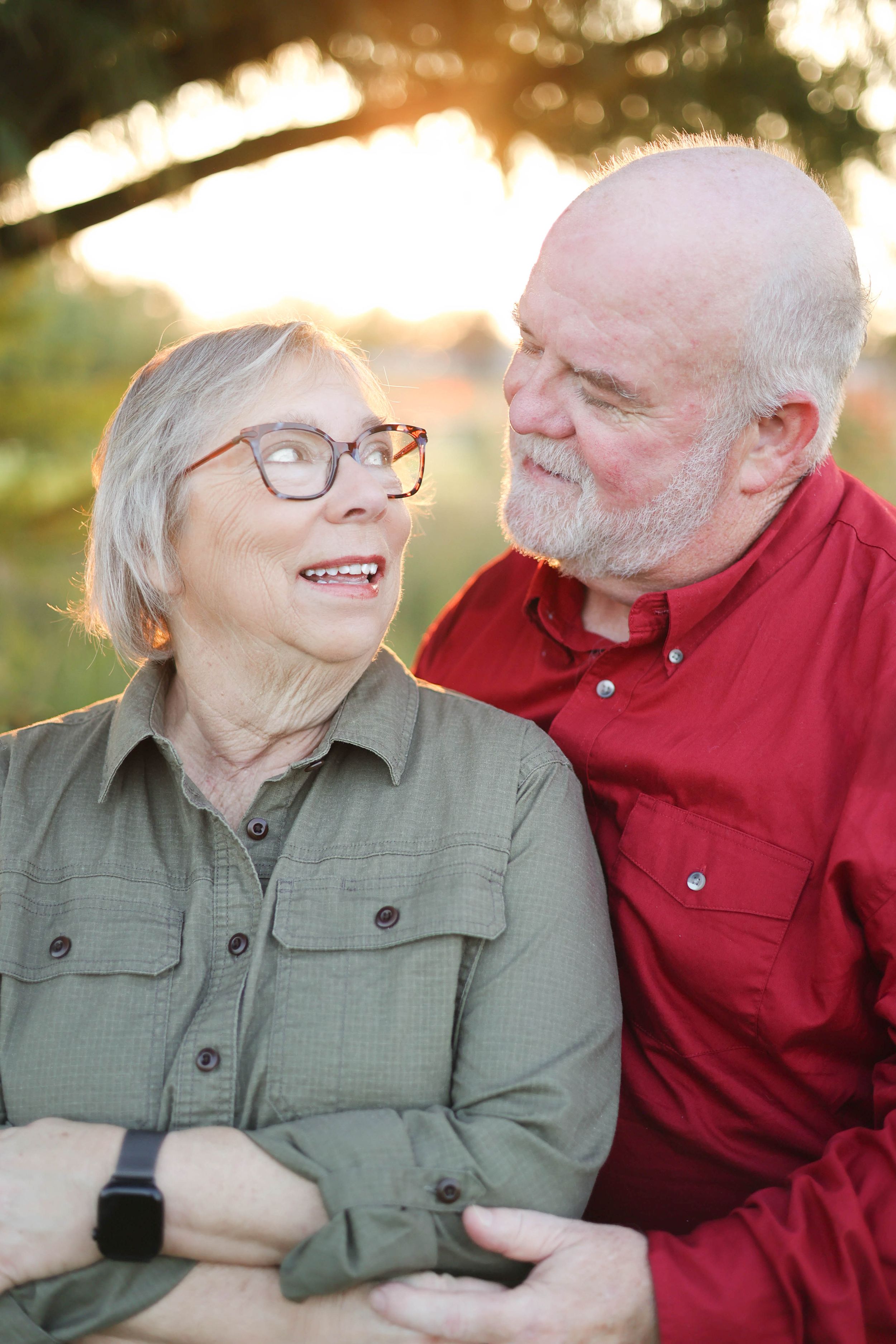 Couple gazing at each other under tree in golden hour glow.