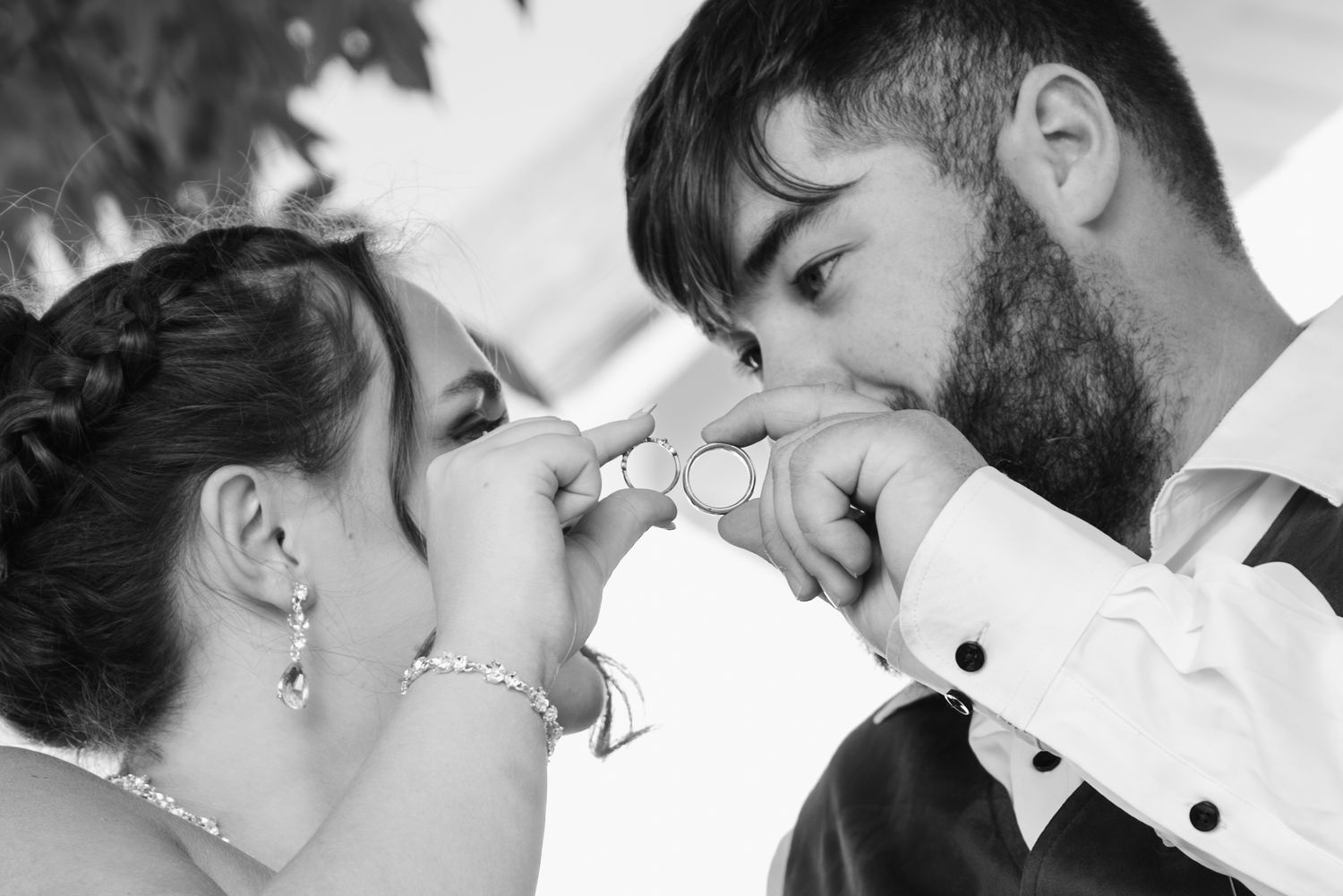 Romantic wedding photo of couple holding their rings up together.