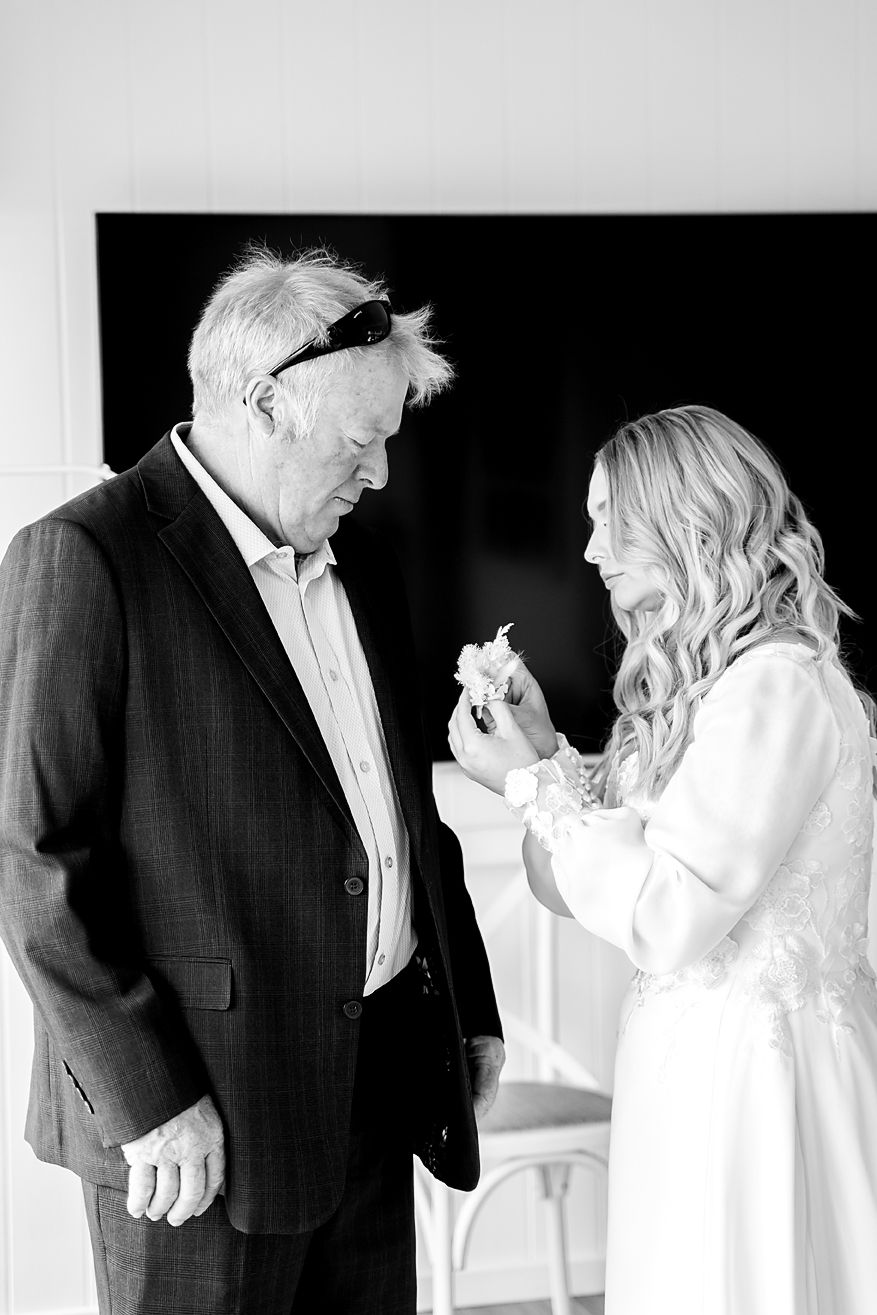 A tender black and white moment between a bride in white and an older man in a suit sharing an emotional exchange.