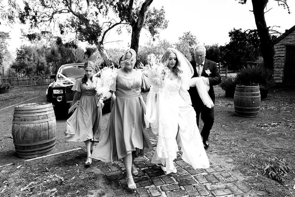 Vintage black and white photograph showing a group dancing together outdoors near wooden barrels.