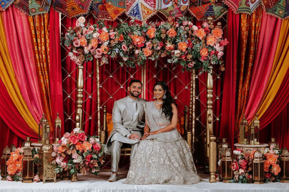 Elegant Indian wedding decor features vibrant red and gold drapes with floral arrangements in a traditional mandap setup.