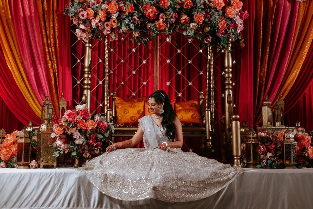 Elegant wedding reception setup with floral arch, crystal drapes, and red velvet curtains creating a luxurious backdrop.