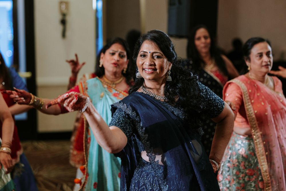 Wedding guests dance joyfully at a reception celebration wearing colorful traditional attire.