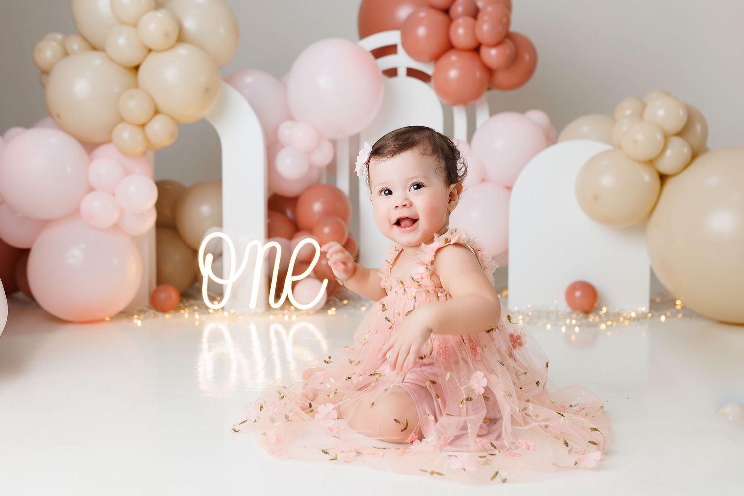 Peach and cream balloon arch decorations with cake smash setup for first birthday celebration.