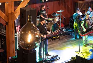 Band performing on stage with colorful lighting effects in rustic barn venue.