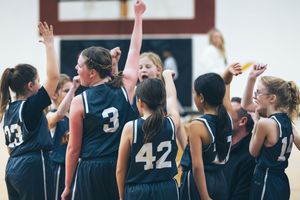 Basketball players in navy uniforms celebrating on court during game.