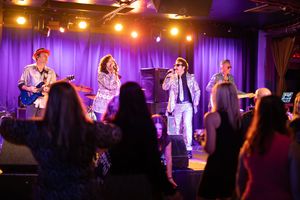 Concert venue with purple stage lighting and performers entertaining an audience.