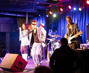 Live music performance on stage with blue and red lighting effects.