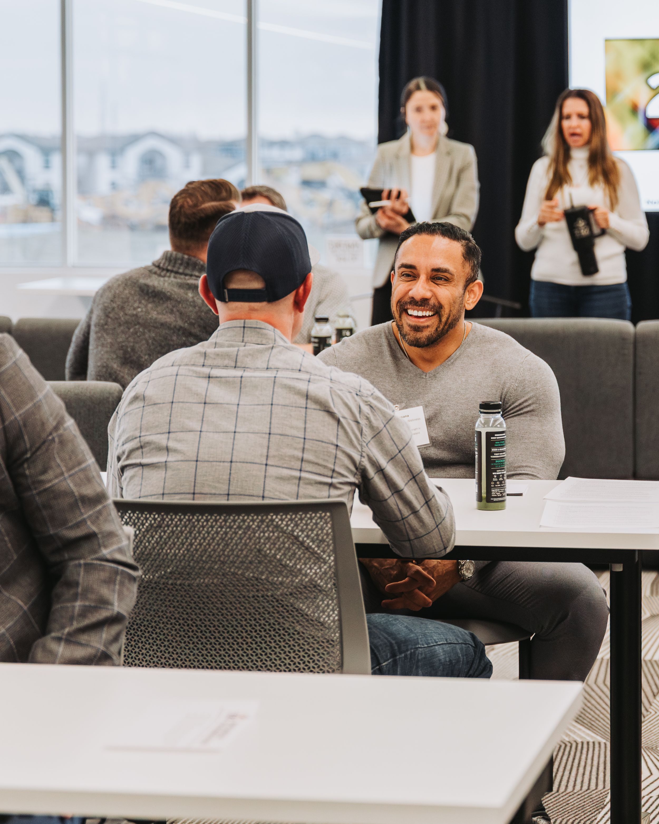 Modern event space with people socializing at tables near large windows.