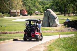 Golf carts driving along a winding path on a scenic golf course.