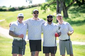Group of golfers in matching attire posing together on a sunny golf course.
