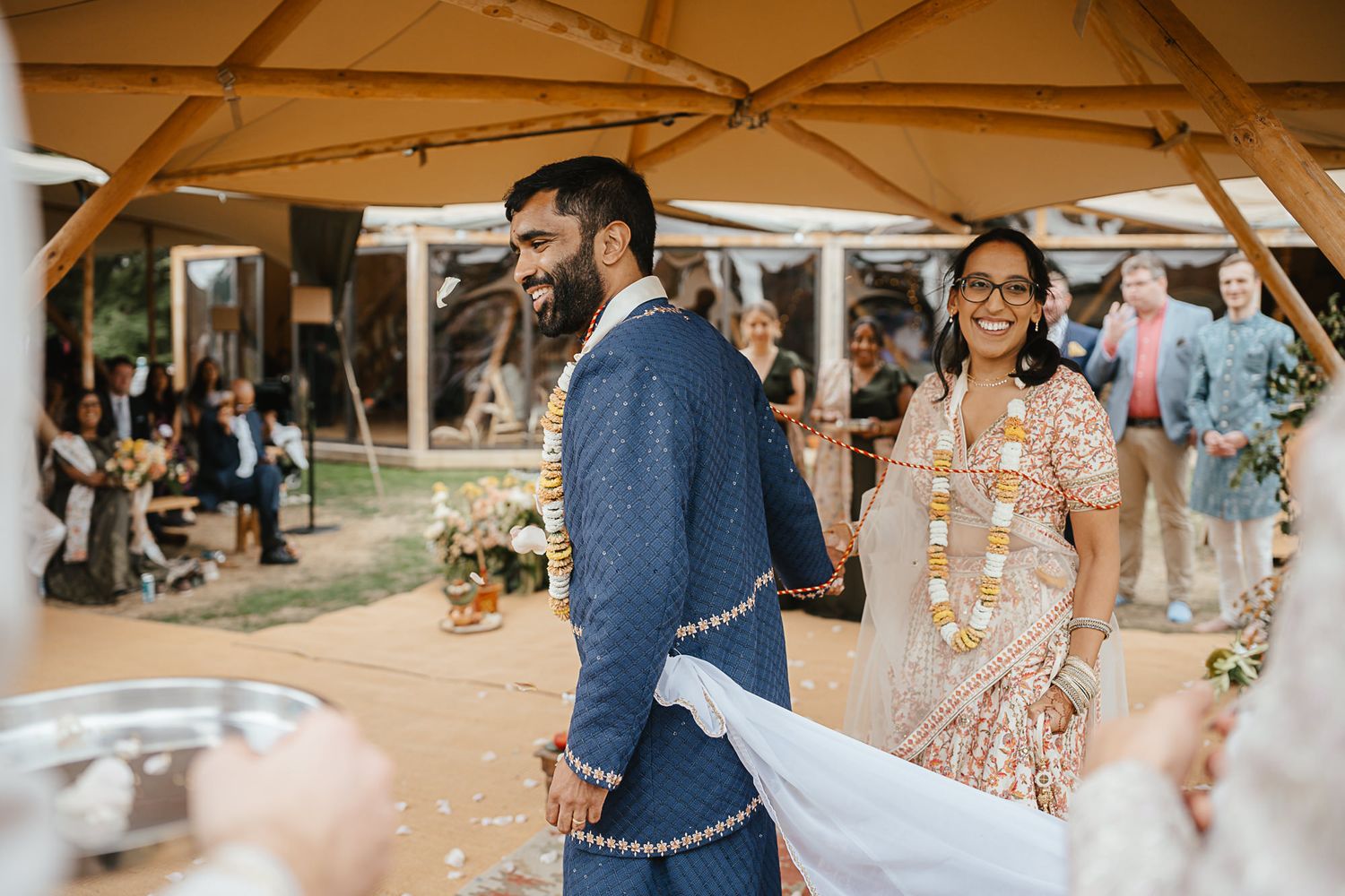 A wedding reception scene with tan umbrellas and string lights creating a romantic outdoor atmosphere.