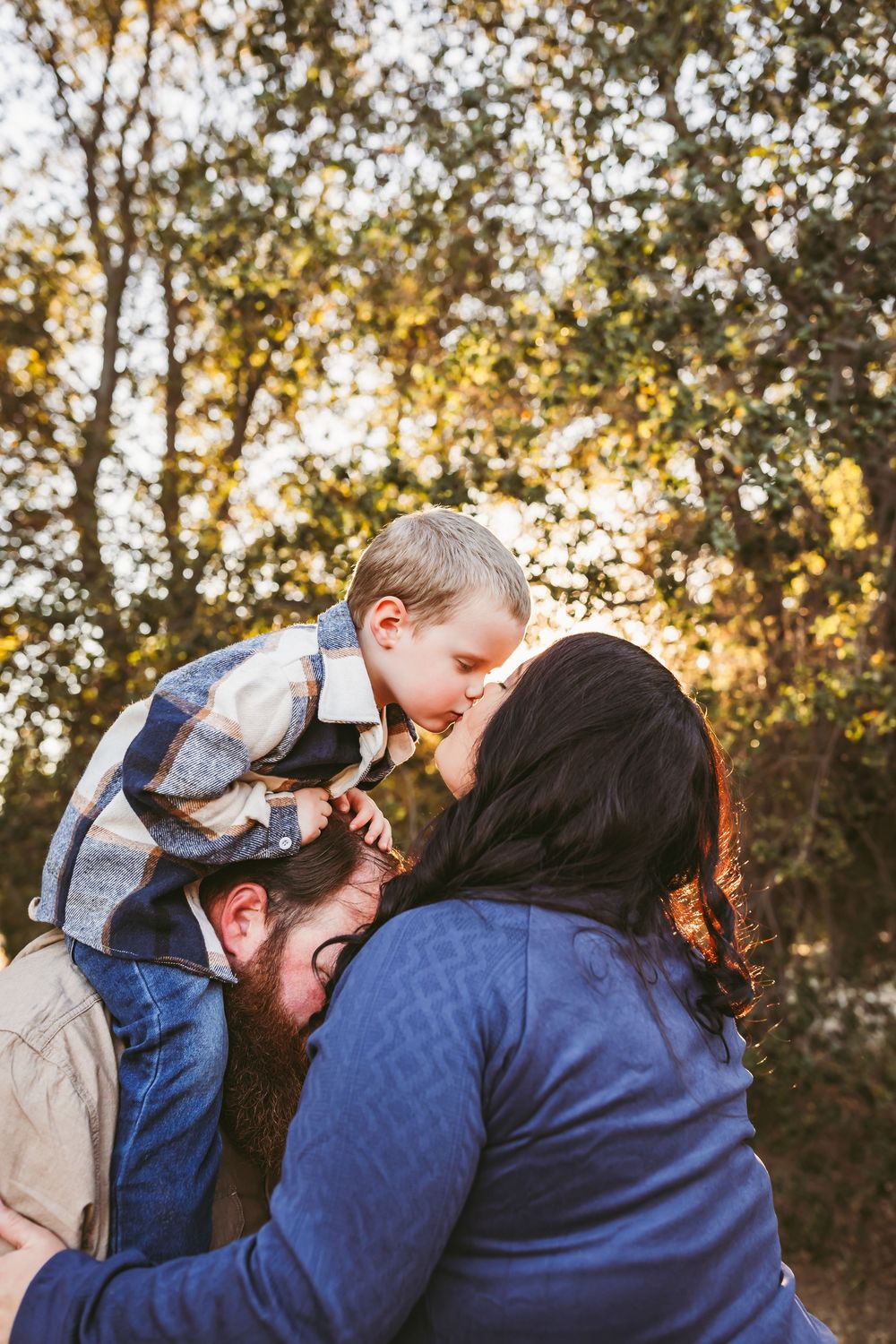 A couple in blue and plaid clothing share an intimate moment outdoors during golden hour.
