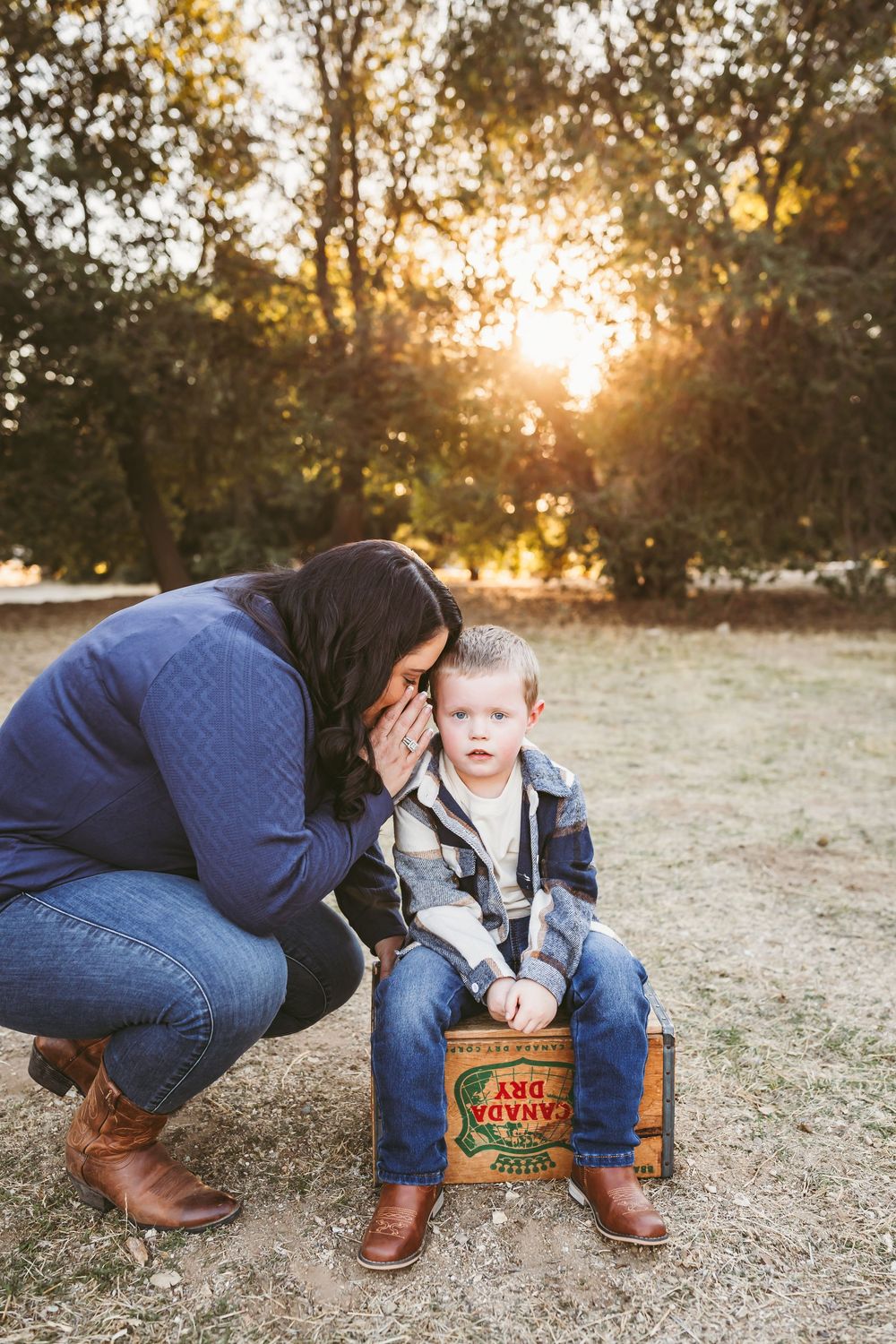 A family plays together near a vintage wooden crate during a sunset photo session.