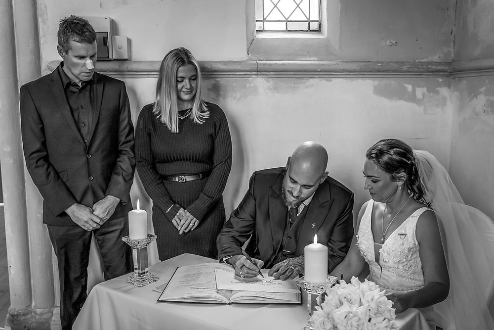 A black and white wedding ceremony scene shows people gathered in a church with light streaming through a window.