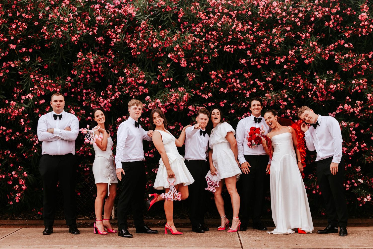 Wedding party group photos against a vibrant red floral backdrop.