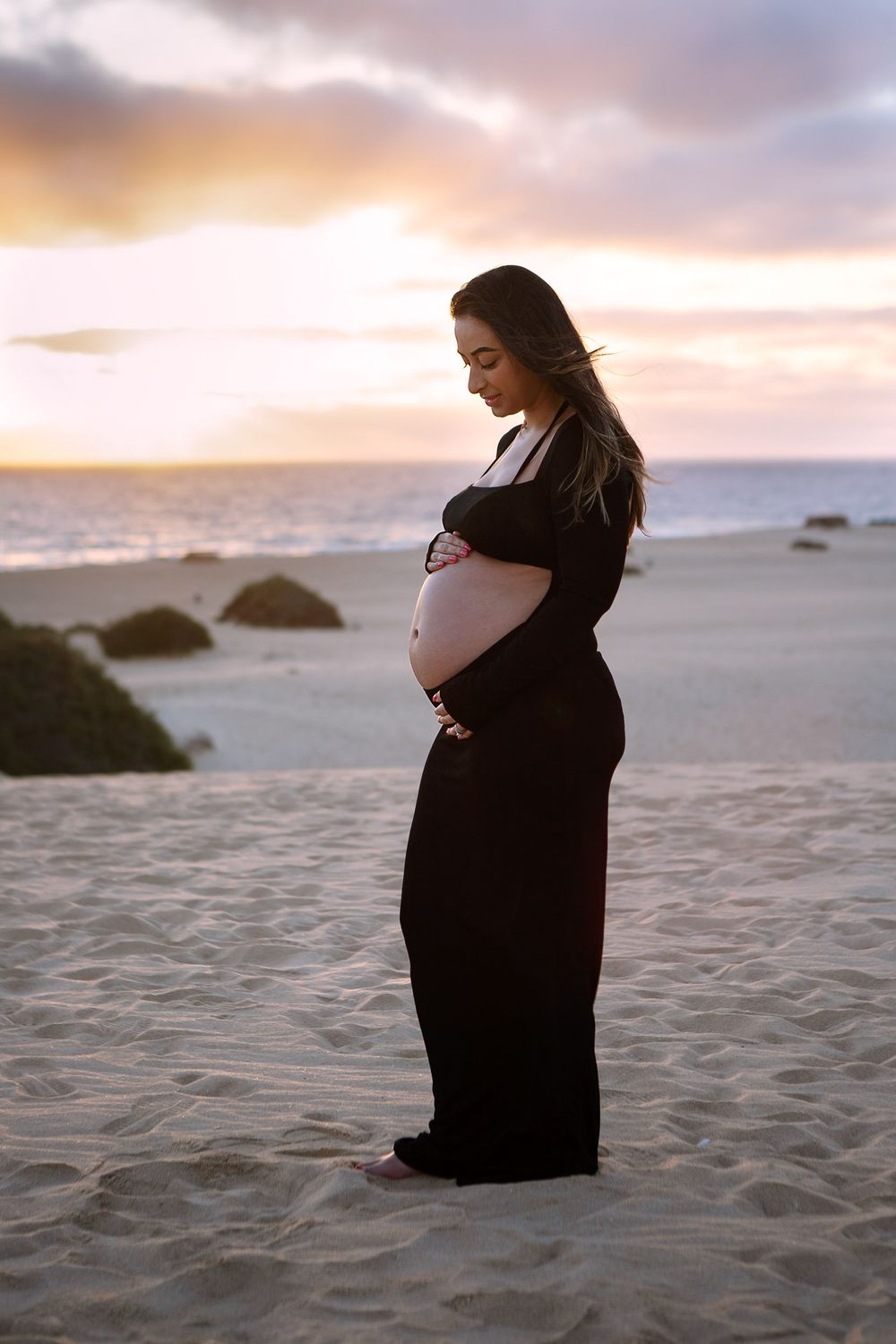 Expectant mother in a long black dress posing on the sand dunes of Grandes Playas at sunset - Fuerteventura maternity photography