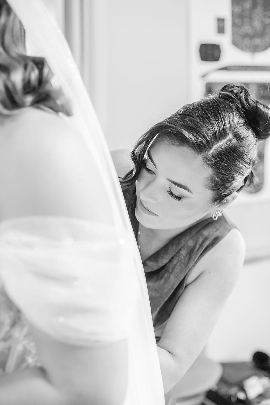 A black and white close-up photo of a bride getting ready on her wedding day with elegant hair and makeup styling.