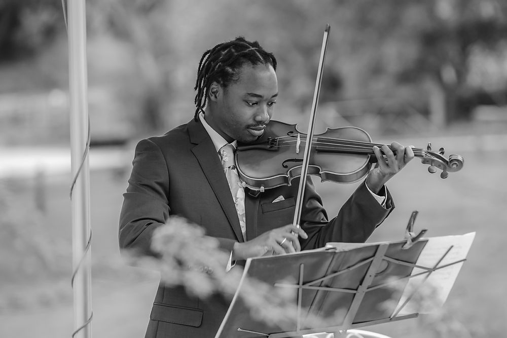 A black and white photo montage shows a musician playing violin while reading sheet music outdoors.