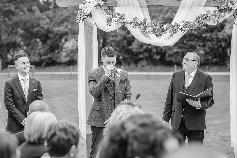 Black and white wedding photo series showing candid emotional moments between guests during an outdoor celebration.