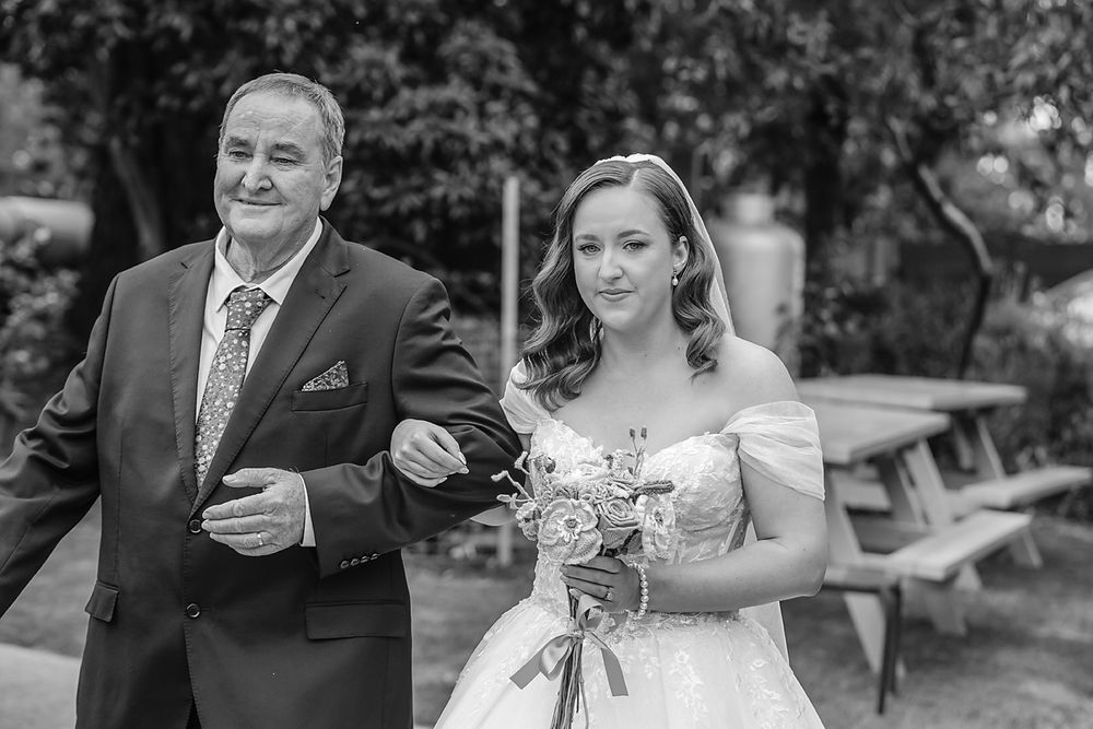 A black and white outdoor wedding portrait with a bride holding a bouquet.