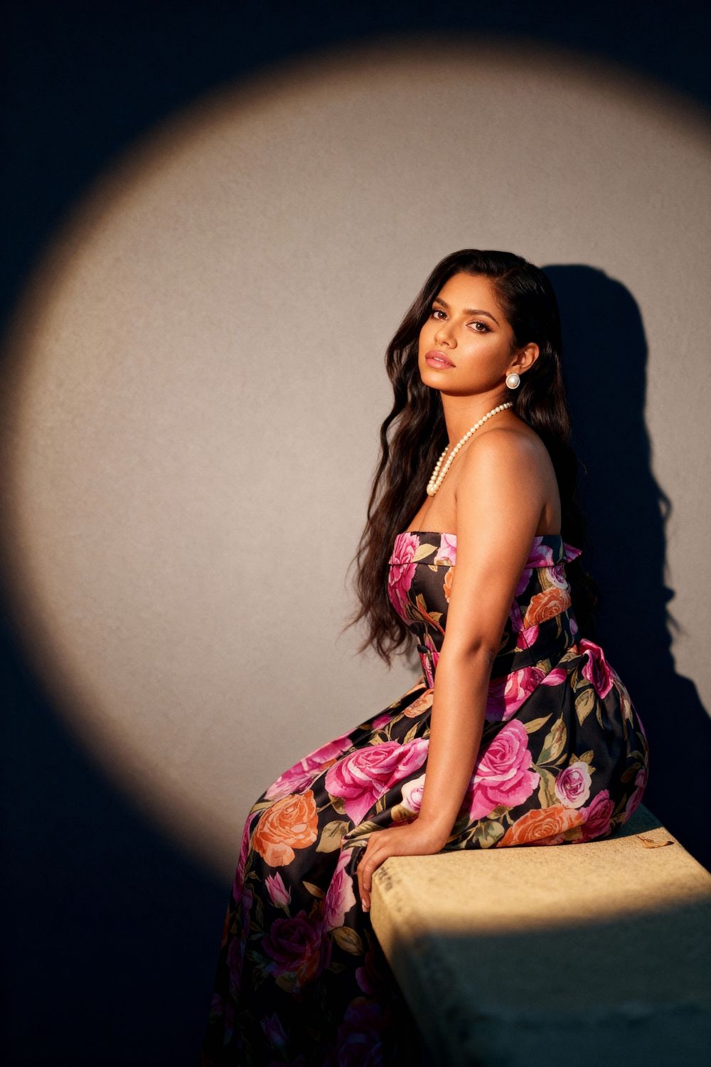 A dramatic portrait series of a woman in a floral dress posing against dark shadows and moody lighting.