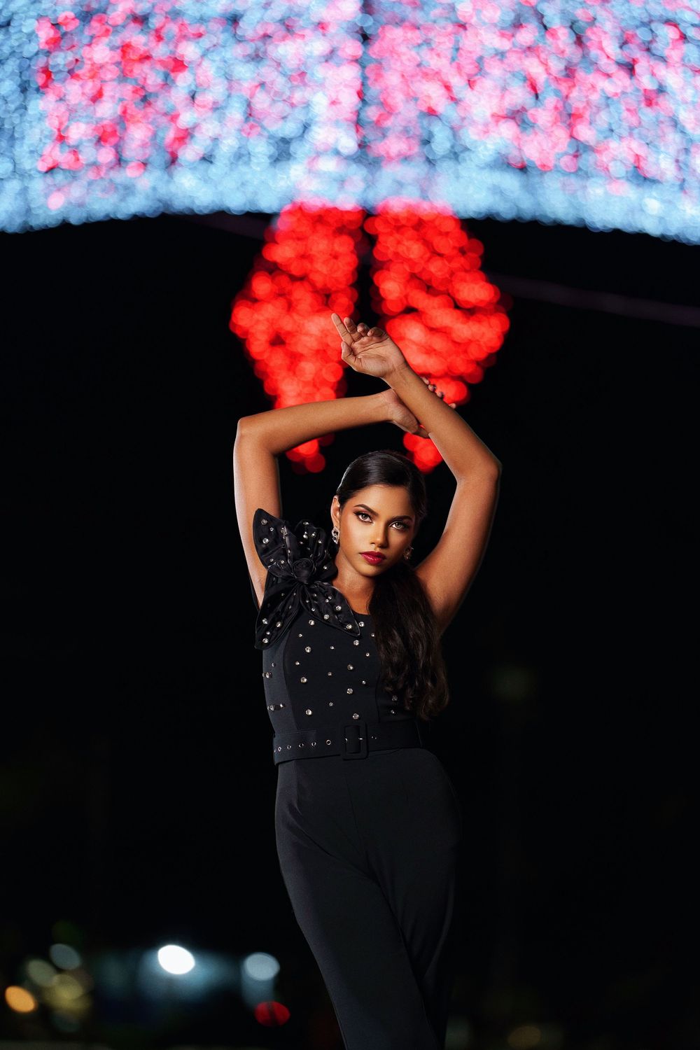 A dancer in a black outfit strikes dramatic poses against a dark background with bright red hair accessories.