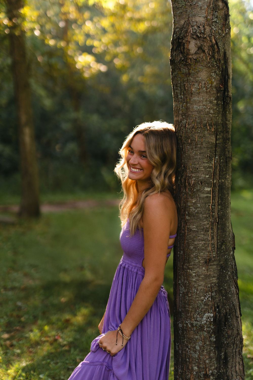 A sequence of outdoor portraits featuring someone in a purple sundress posing against a tree in golden evening light.