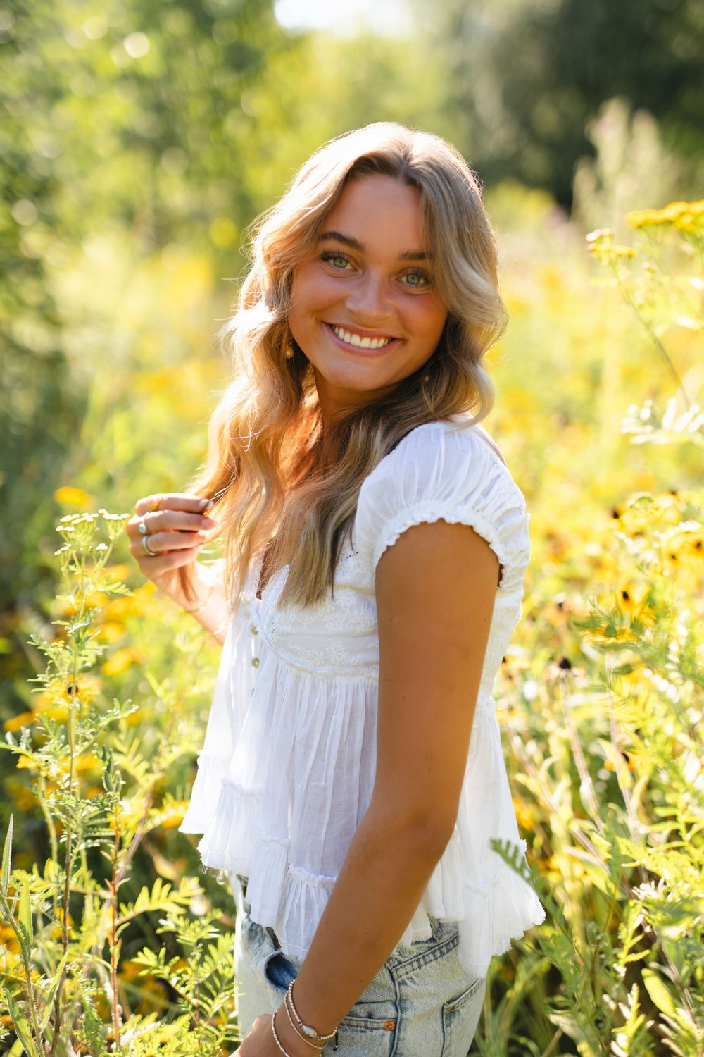 A white lace top and sunny wildflowers create a dreamy summer portrait session in golden afternoon light.